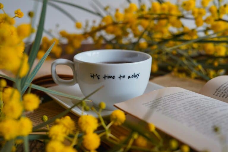 A serene setting with a tea cup, open book, and bright yellow flowers for relaxation.