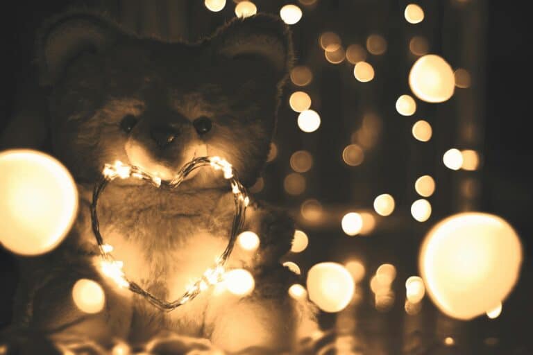 A warm, enchanting scene of a teddy bear adorned with heart-shaped string lights, creating a cozy atmosphere.